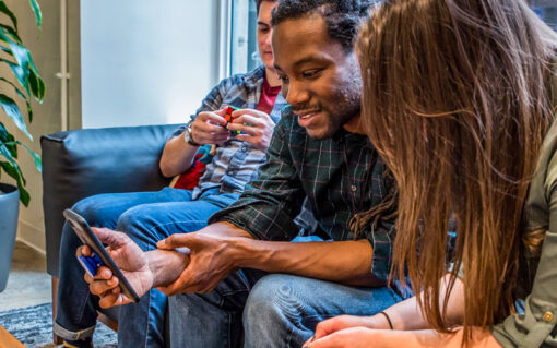 Three people chatting and looking at cell phone screen